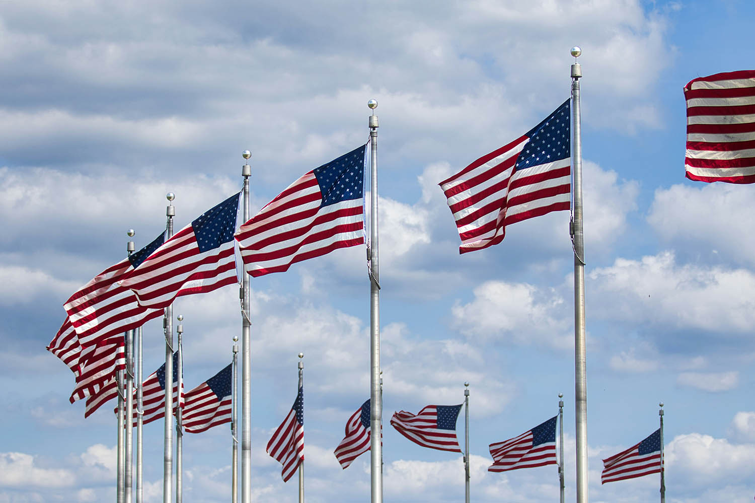 American flags against a blue sky with clouds